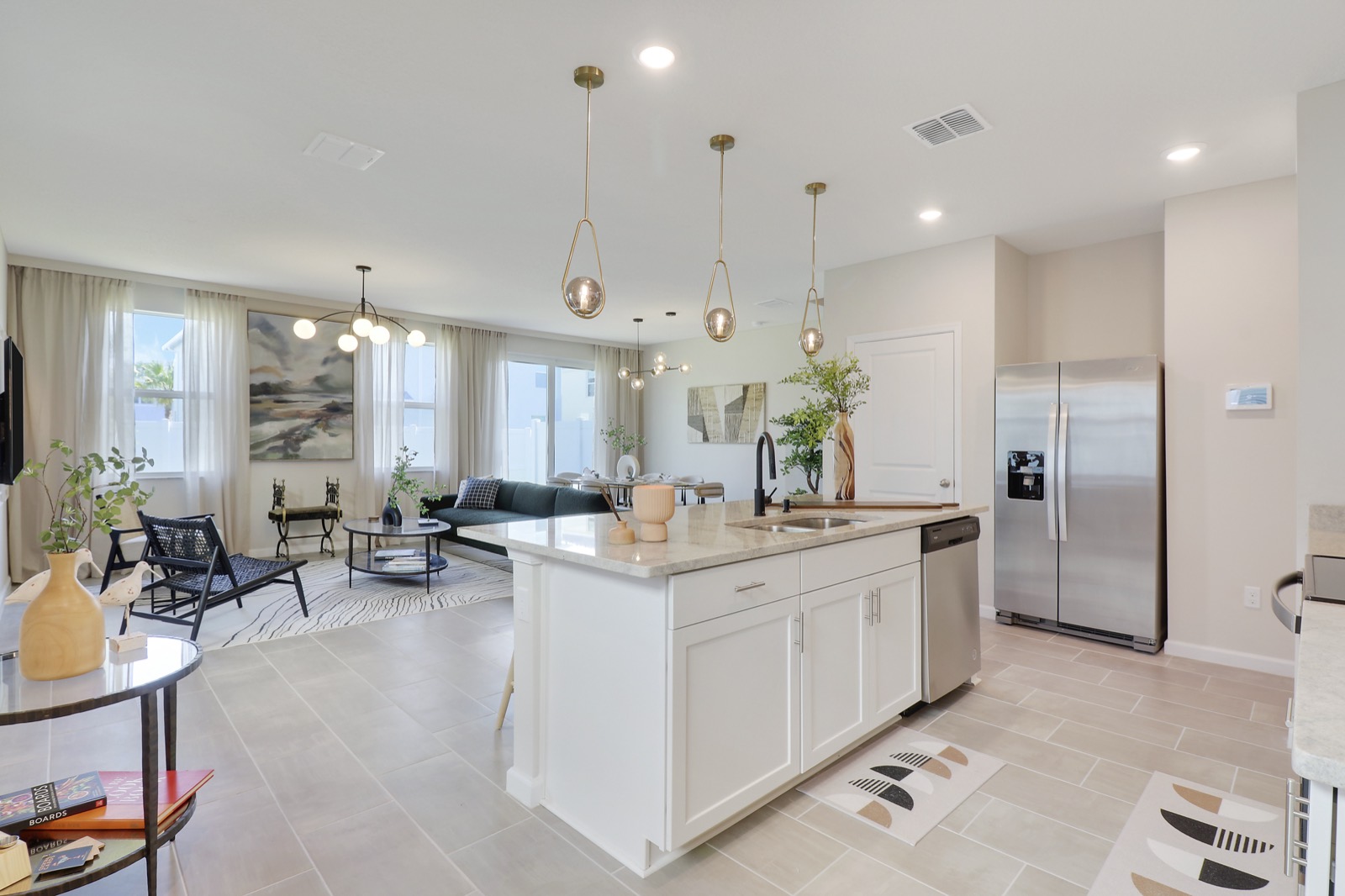 Kitchen and living room at 261 Osprey Preserve with brass pendants over a white island and the living room beyond