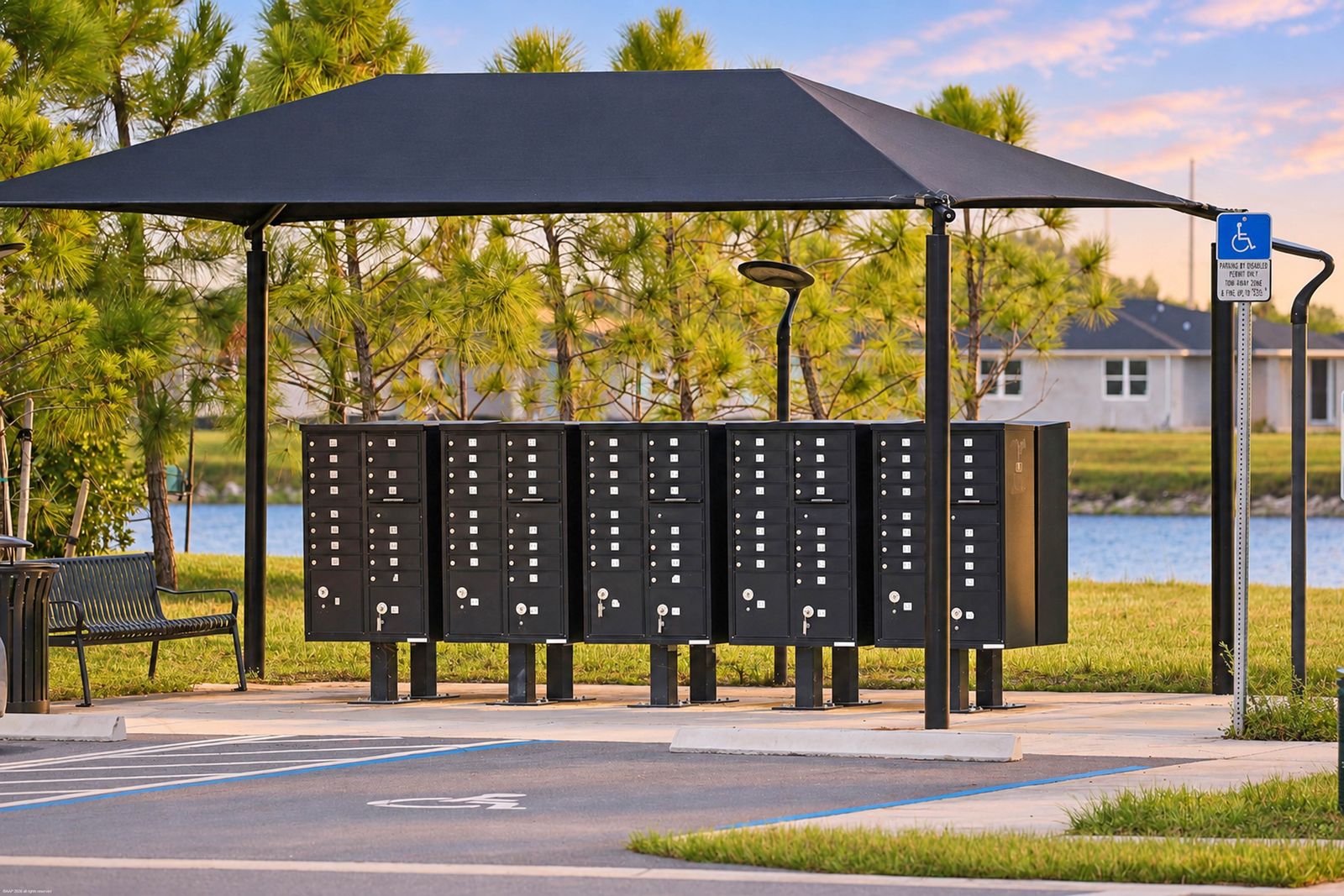 Covered community mailbox kiosk with a bench beside the lake